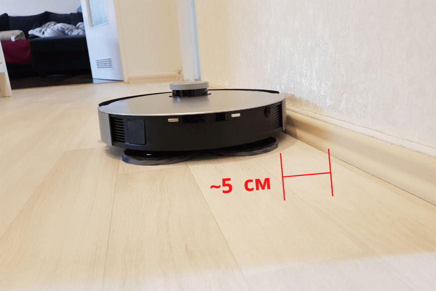 Ein Saugroboter reinigt entlang einer Fußleiste.